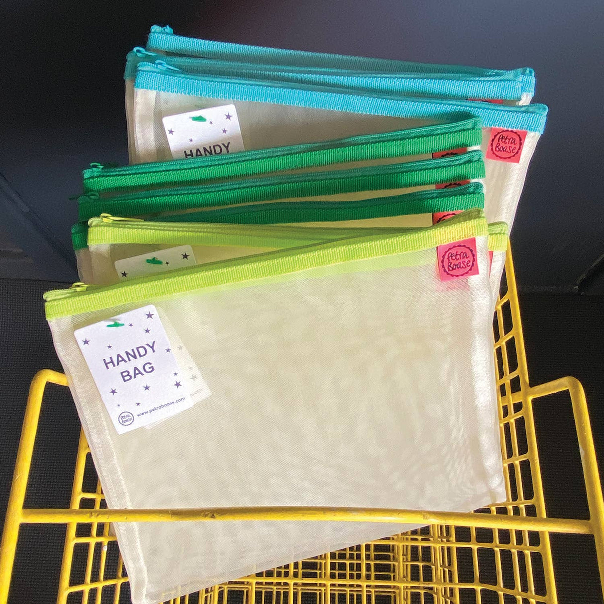 Set of colorful pouches with labels on a yellow metal frame against a dark background