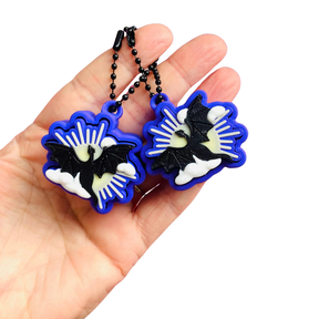 Hand holding two dragon-shaped keychains with blue borders on a white background