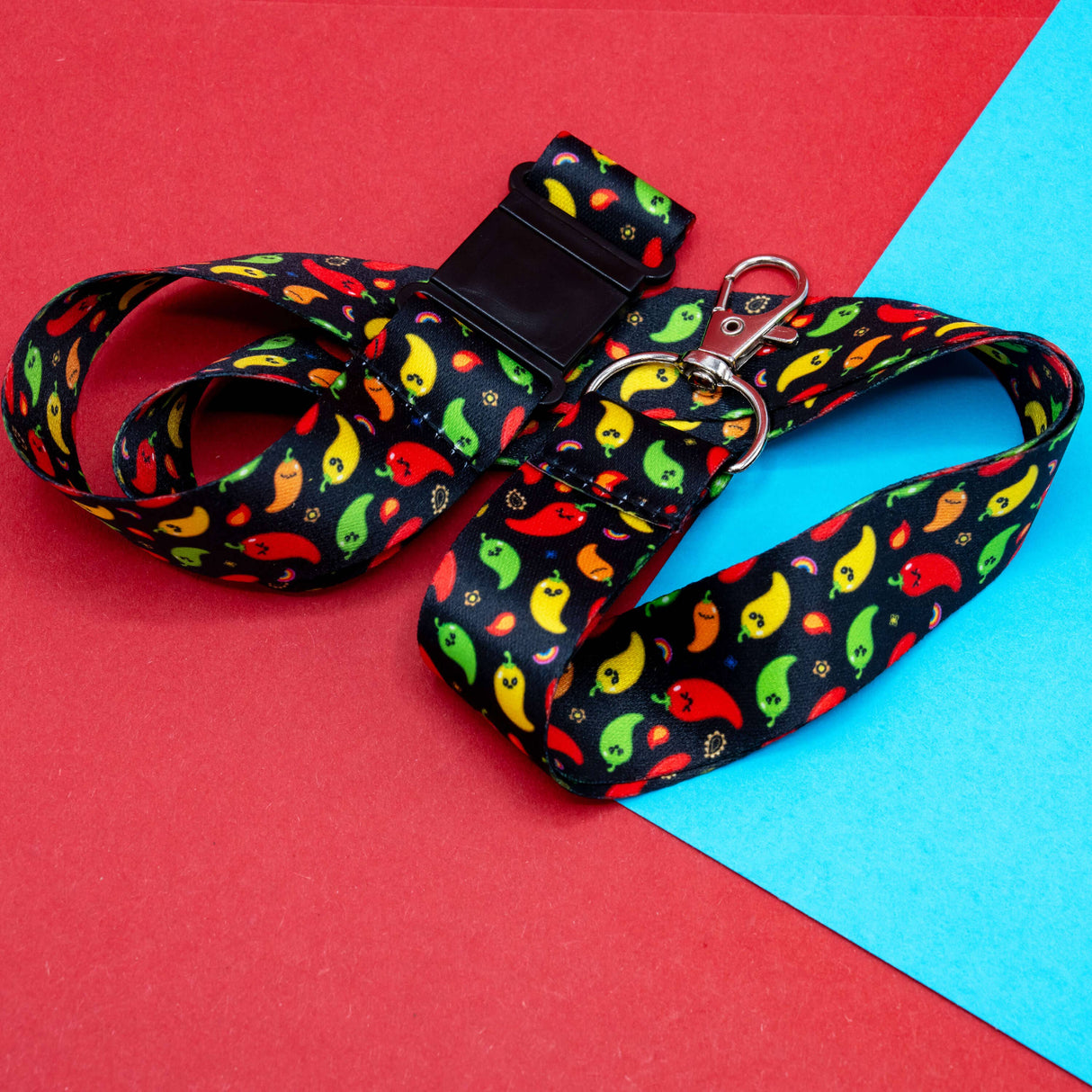 black chili pattern lanyard with colourful peppers and silver clasp on red blue background