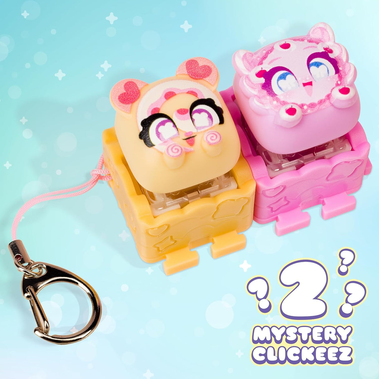 Two small character-shaped keychain clickers on a light blue background with a metal key ring and the text 'Mystery Clickeez 2' in the lower right.
