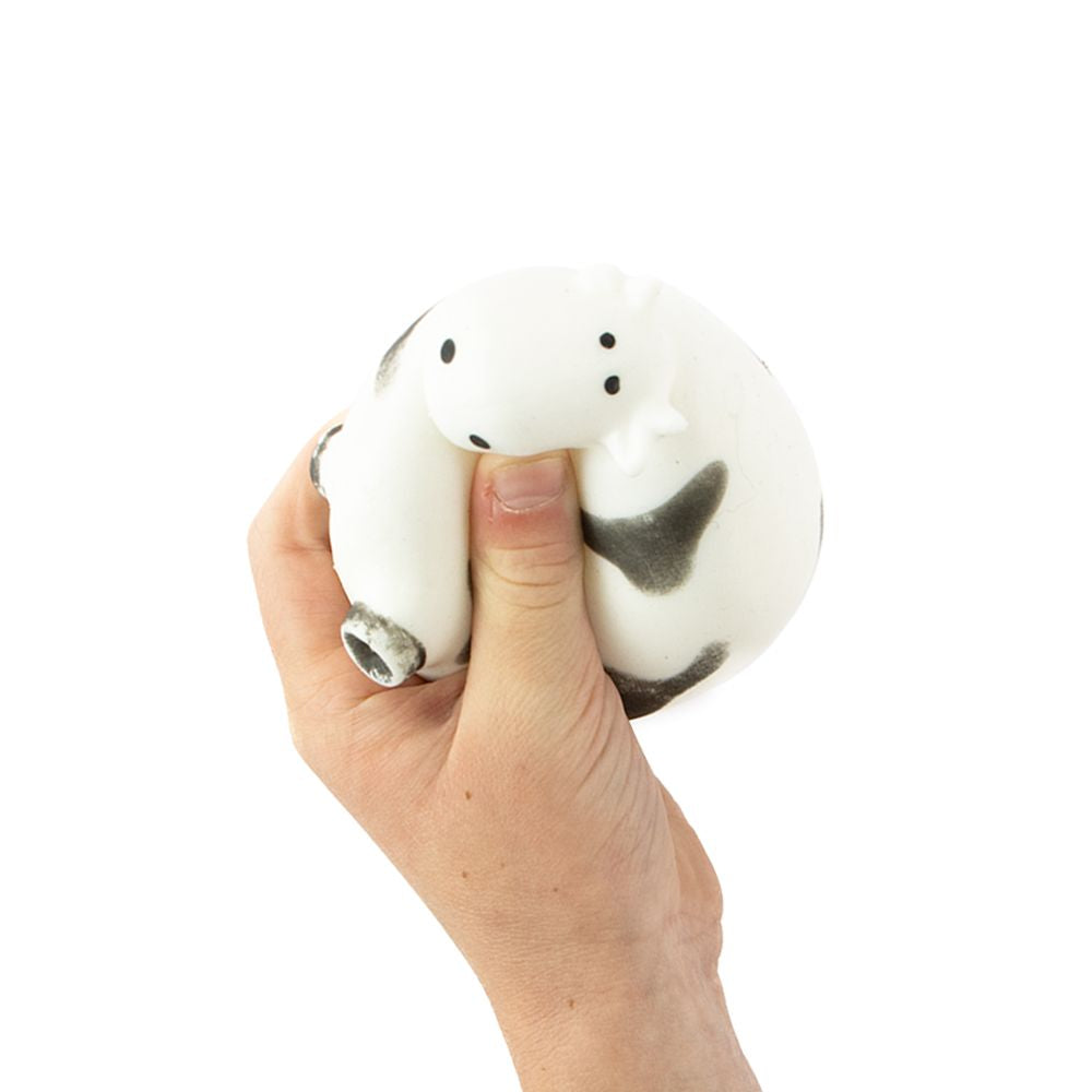 Hand squeezing Farm Squeezies black and white cow squishy sensory toy demonstrating soft flexible texture