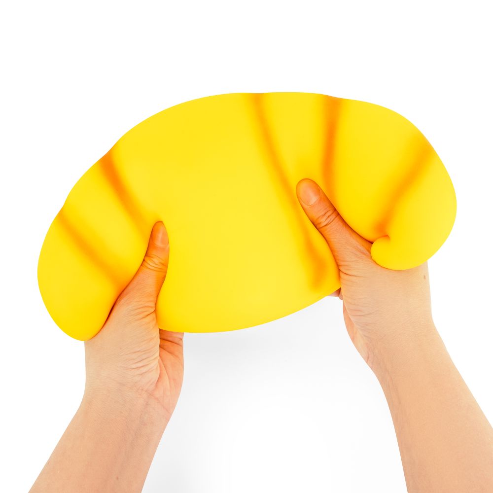 Two hands holding Jumbo Squishy Croissant showing oversized size and soft slow-rise stretchy sensory fidget toy