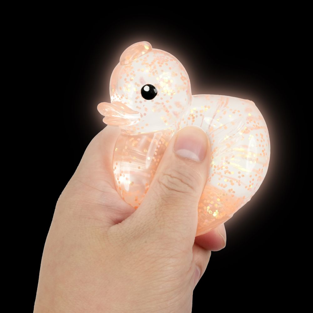 Hand squeezing Keycraft glow in the dark squishy duck with peach glitter glowing in darkness