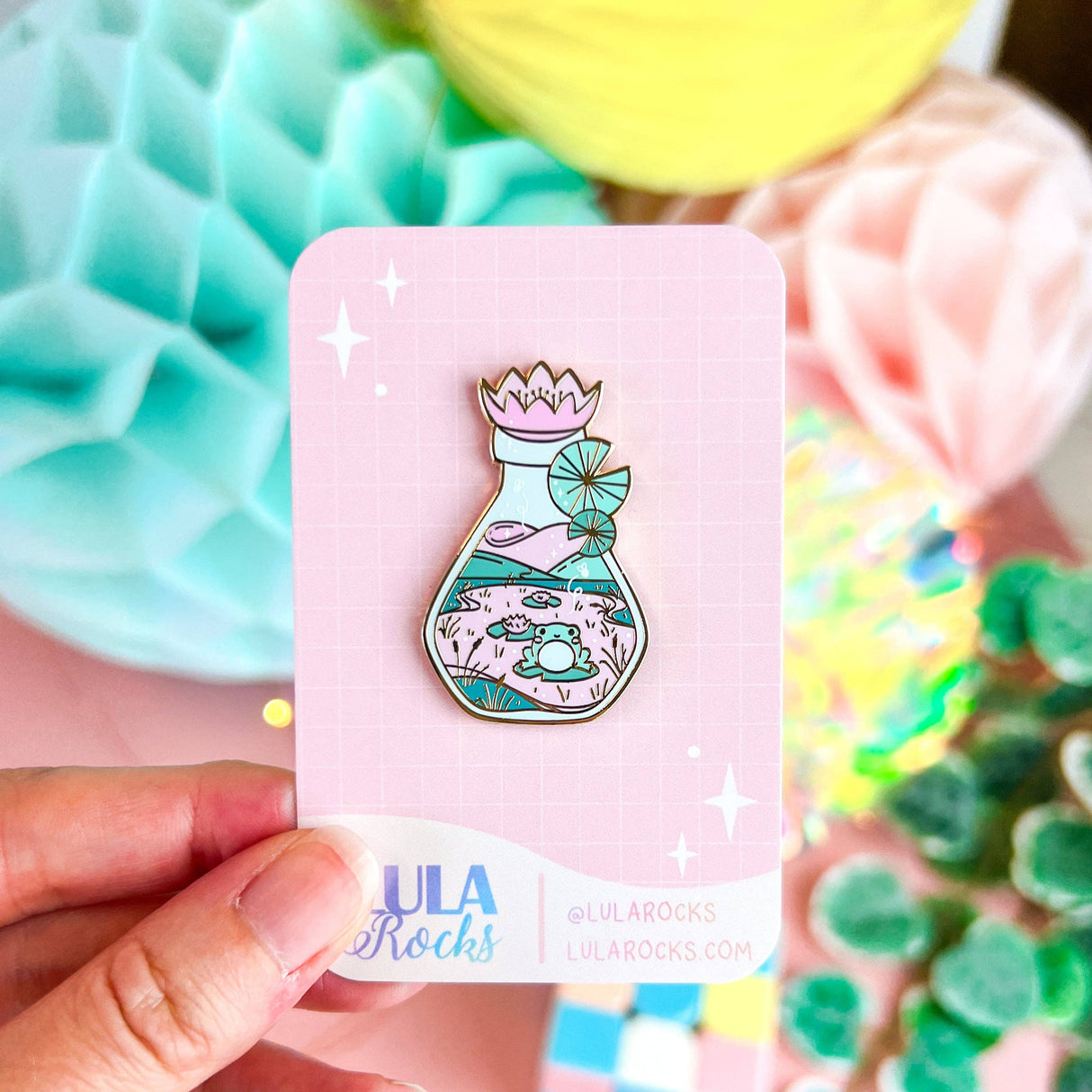 Lula Rocks Bottled Frog UV Glow pin on backing card, pastel pink teal colorway