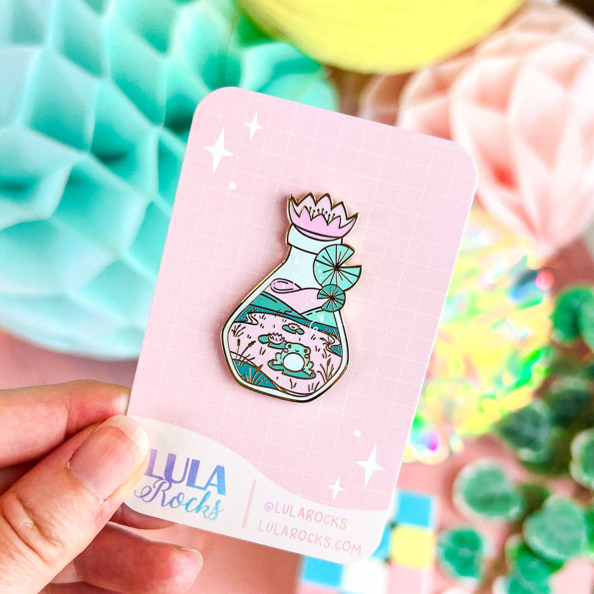 Lula Rocks Bottled Frog UV Glow enamel pin, pastel pink teal, colourful block props