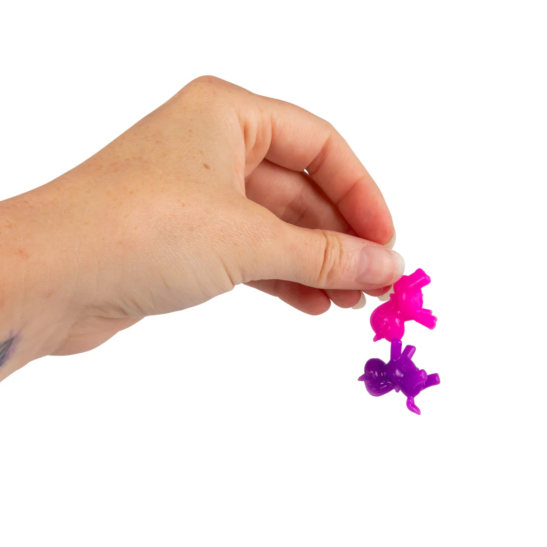 Adult hand holding two micro unicorn fidget figures in pink and purple