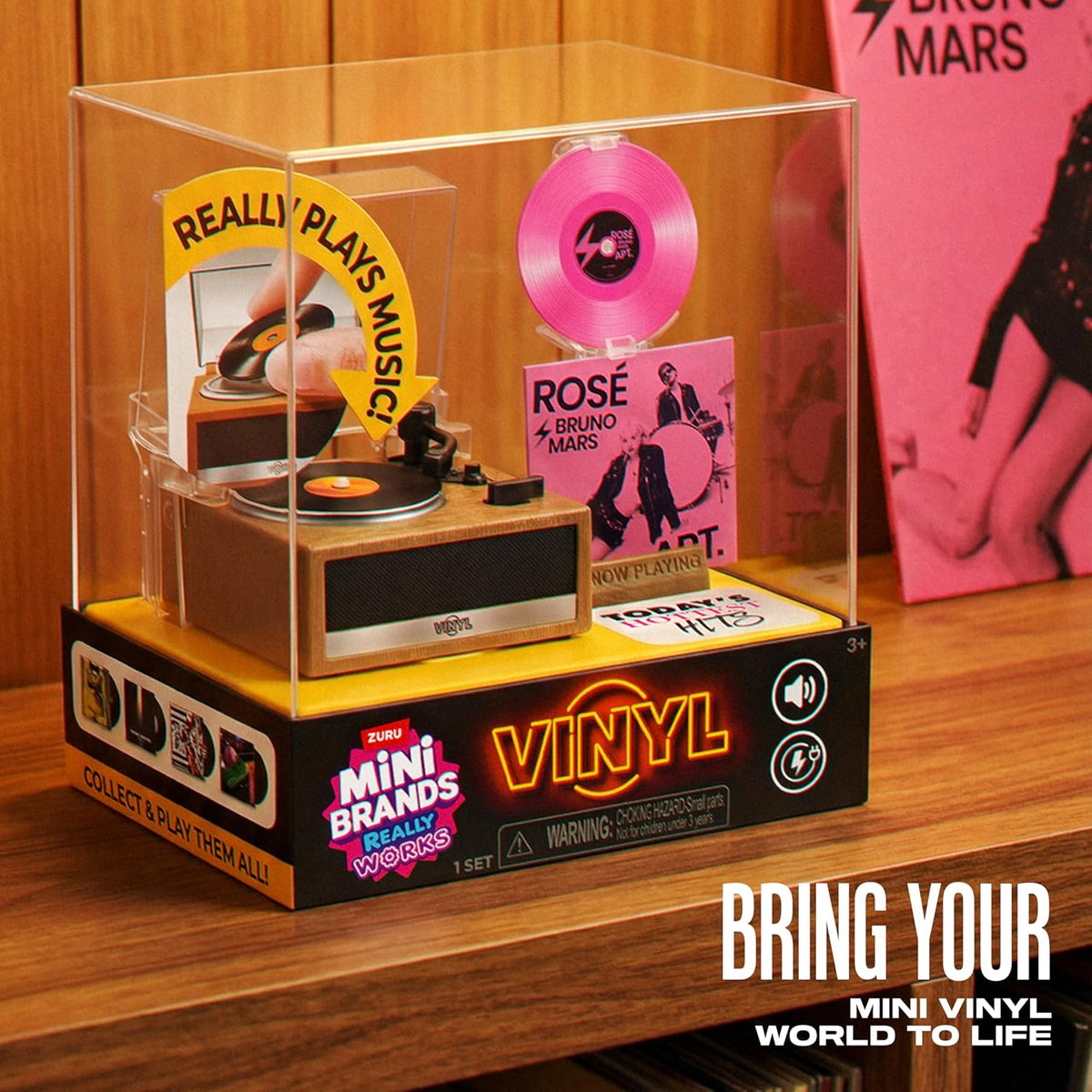 Mini Brands Really Works Vinyl playset display case on wooden shelf beside record sleeve