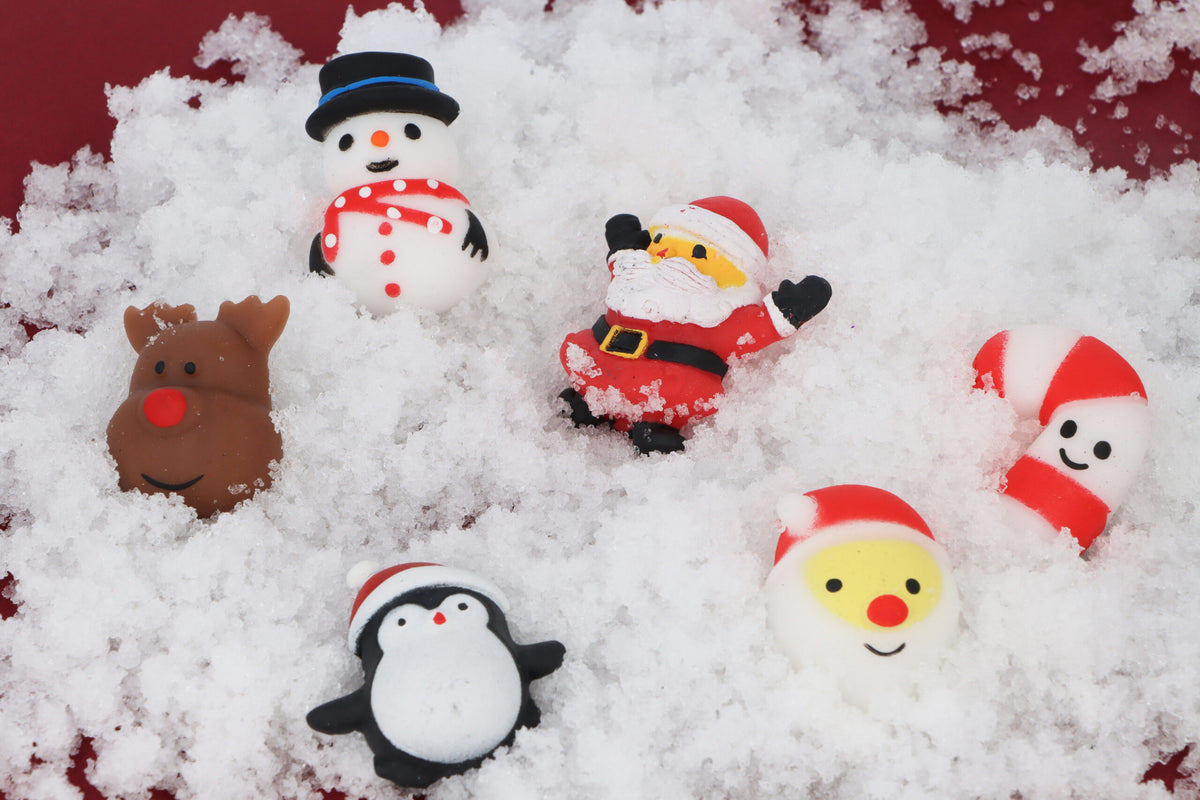 Six mini Christmas squishy toys scattered in snow with Santa and reindeer designs
