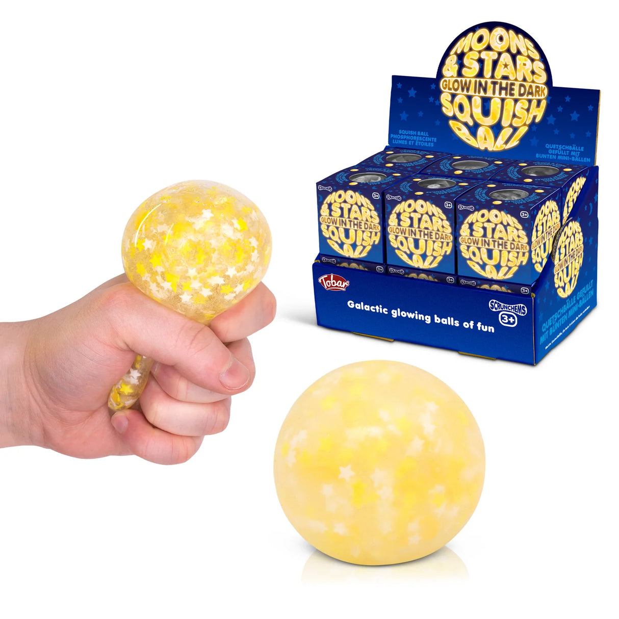 Scrunchems Moons and Stars glow in the dark squish ball being squeezed in a hand alongside retail display box