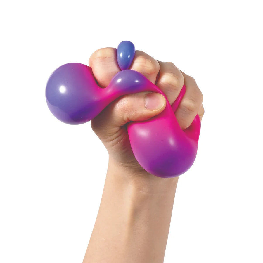 Hand squeezing a pink Nee Doh Colour Change ball revealing a vivid purple colour shift