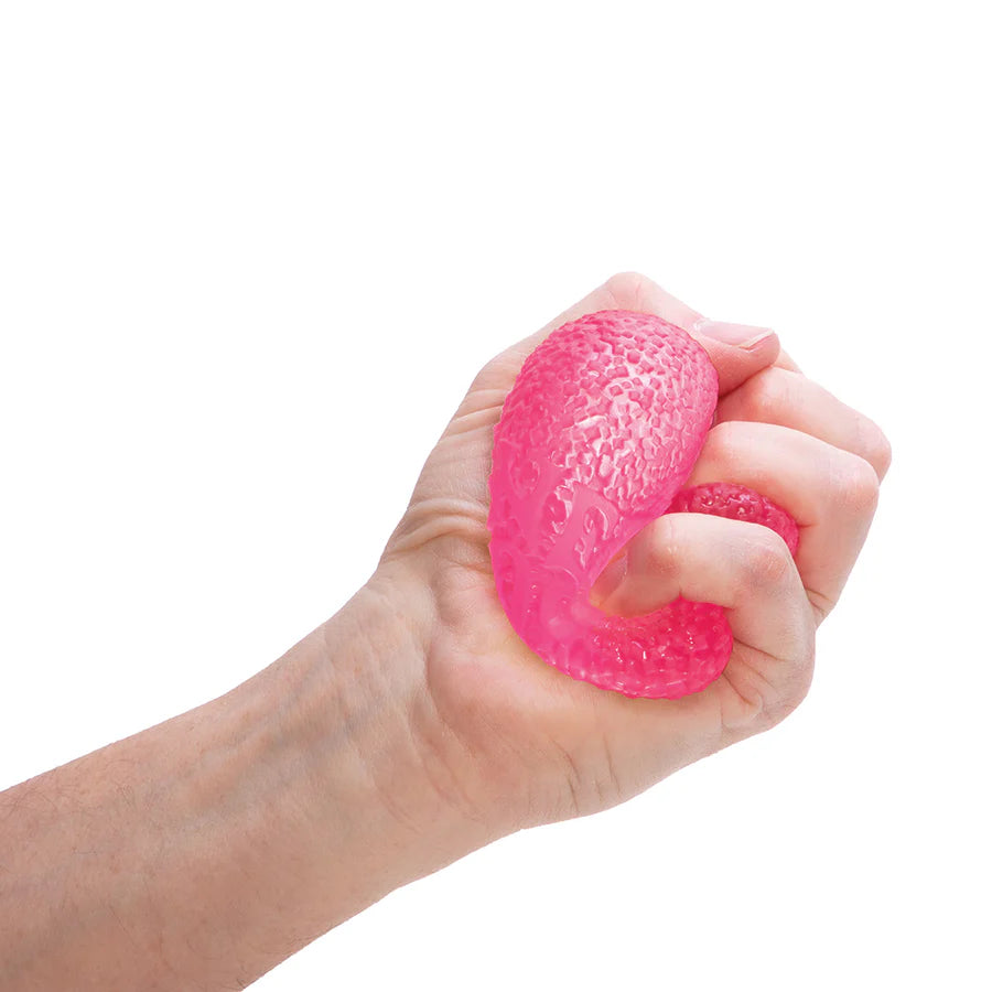 Pink Nee Doh Gumdrop being squeezed in a fist showing textured gel surface and solid squish