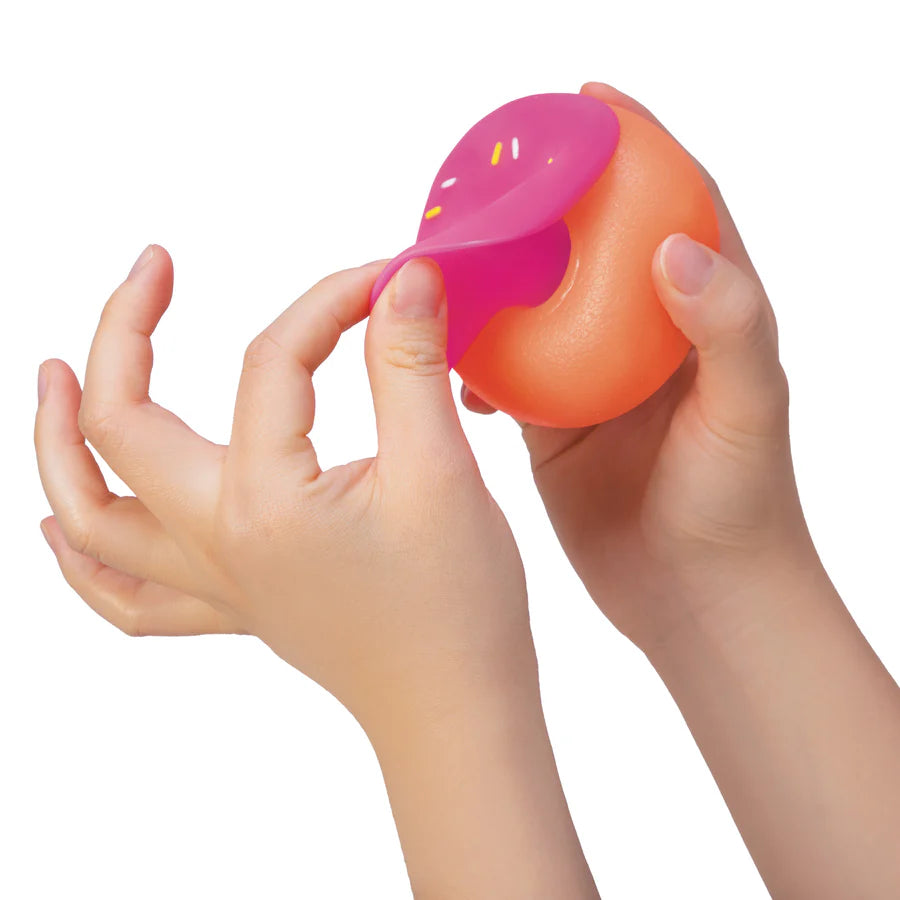 Pink frosting top of a NeeDoh Dohnut being peeled back to show the swappable two-piece design