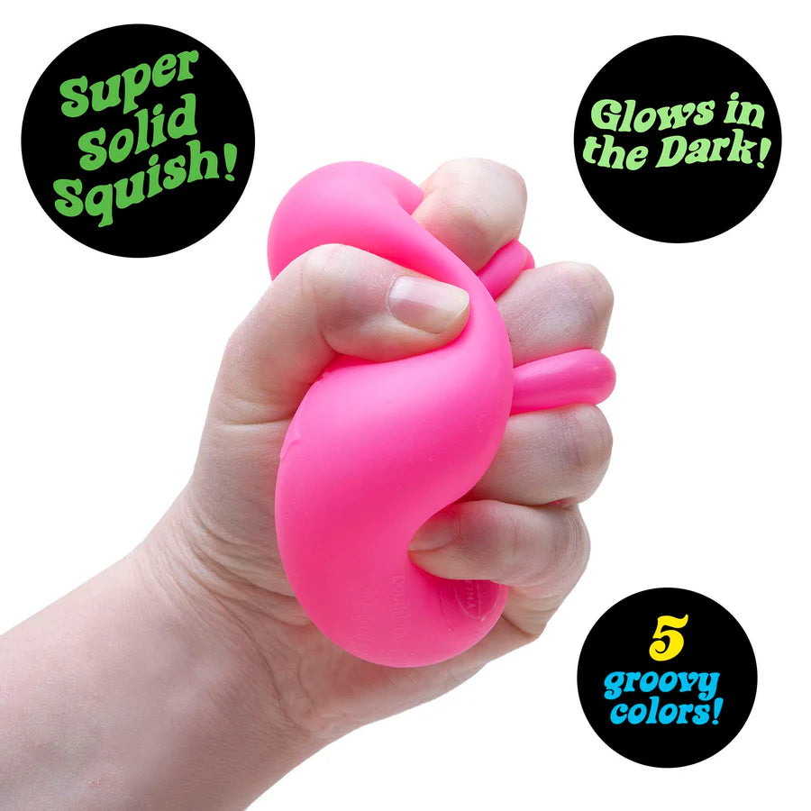 Hand squeezing a pink Nee Doh Nice Cube Glow showing super solid squish texture and deformation
