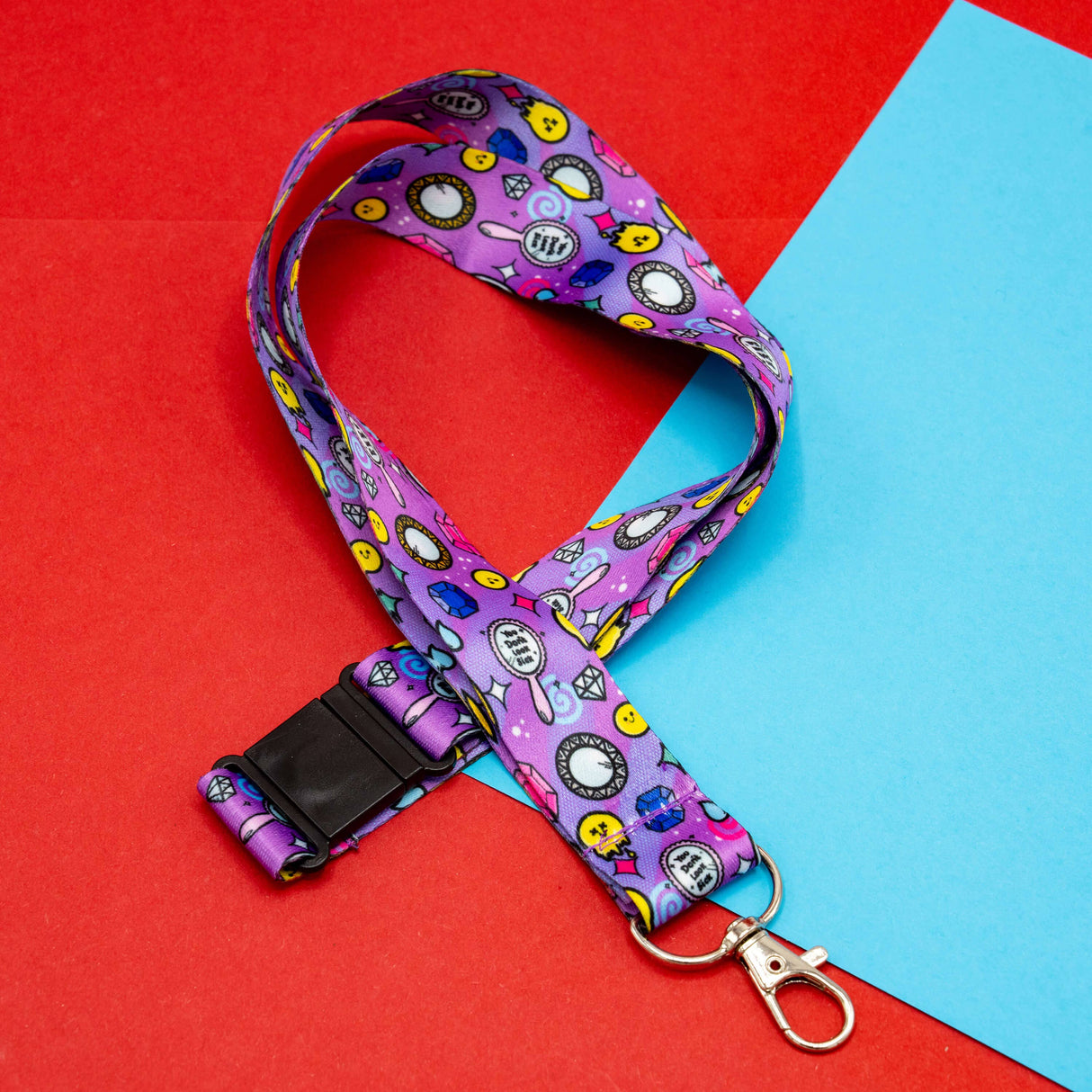purple lanyard with colourful smiley diamonds clocks and hearts pattern with clasp