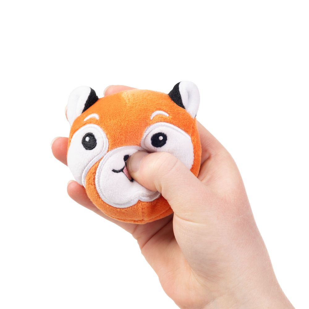 Hand squeezing a kawaii red fox plush sensory toy showing soft sugar-filled compression and white face markings