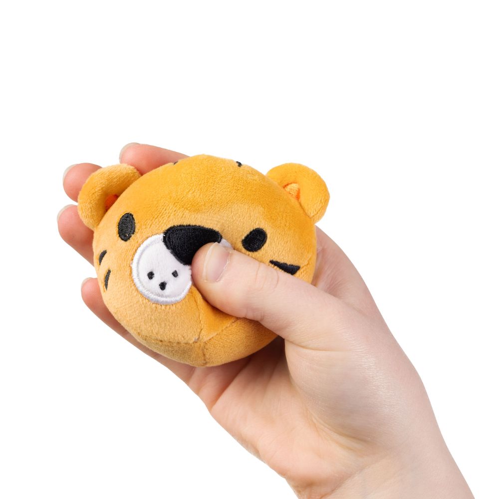 Hand squeezing a kawaii tiger plush sensory toy showing soft sugar-filled compression and embroidered muzzle detail