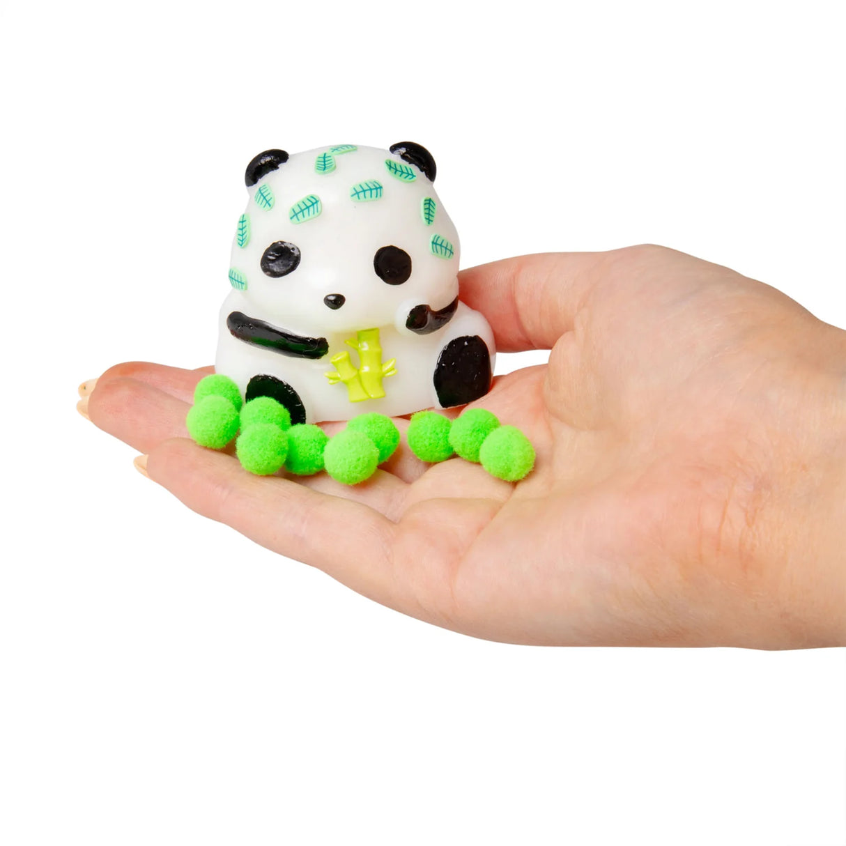 White squishy panda with bamboo leaf print and neon green sticky pom-pom balls displayed on an open palm
