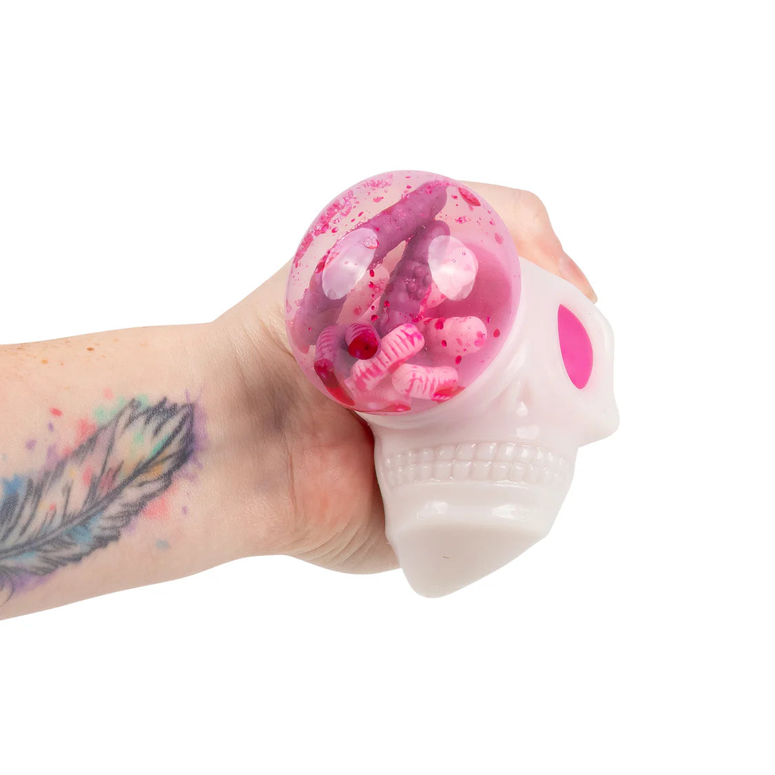 Adult hand squeezing the skull squishy hard, showing the clear dome filled with pink gloop, worms and eyeball inclusions bulging out