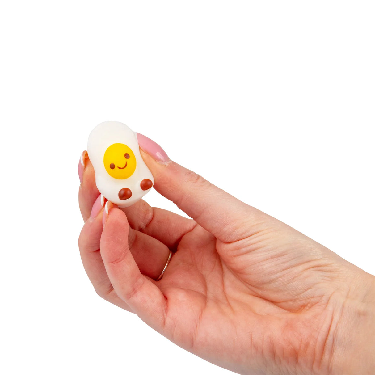 Hand holding a smiling fried egg kawaii squishy fidget toy from the Bakery set