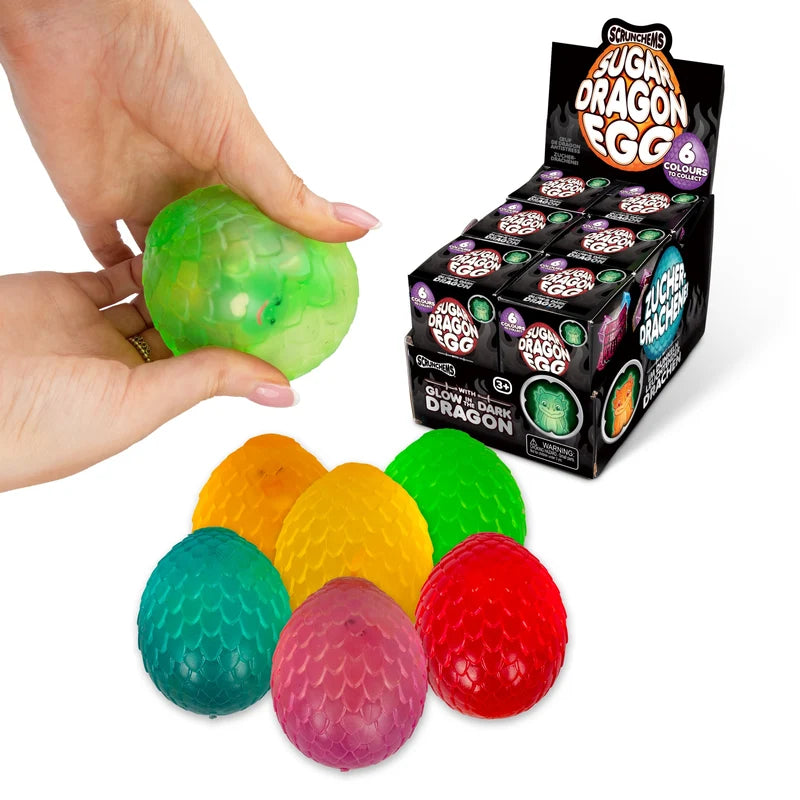 Display box of Scrunchems Sugar Dragon Eggs with hand squeezing green egg and six colours shown