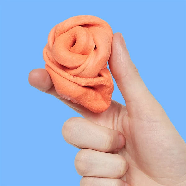 Hand shaping clementine orange sensory putty into a rose-like swirl for stimming