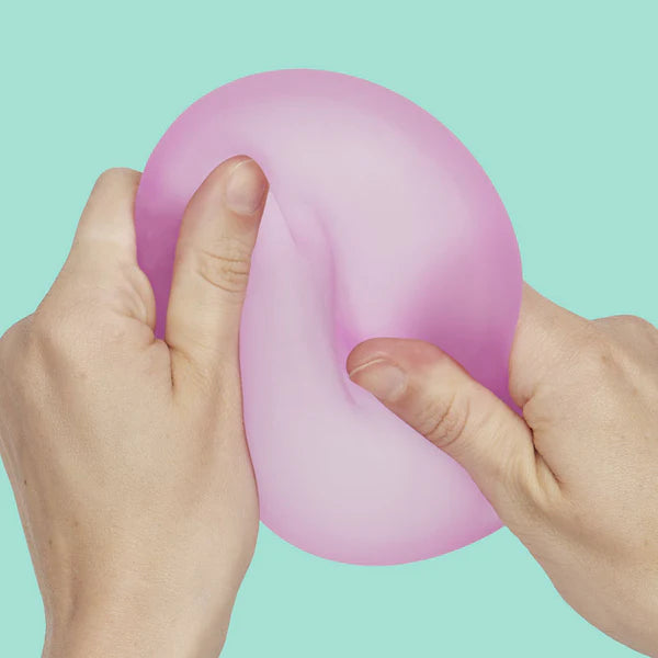 Two hands squeezing and deforming pink Speks Gump Jumbo Loop fidget toy