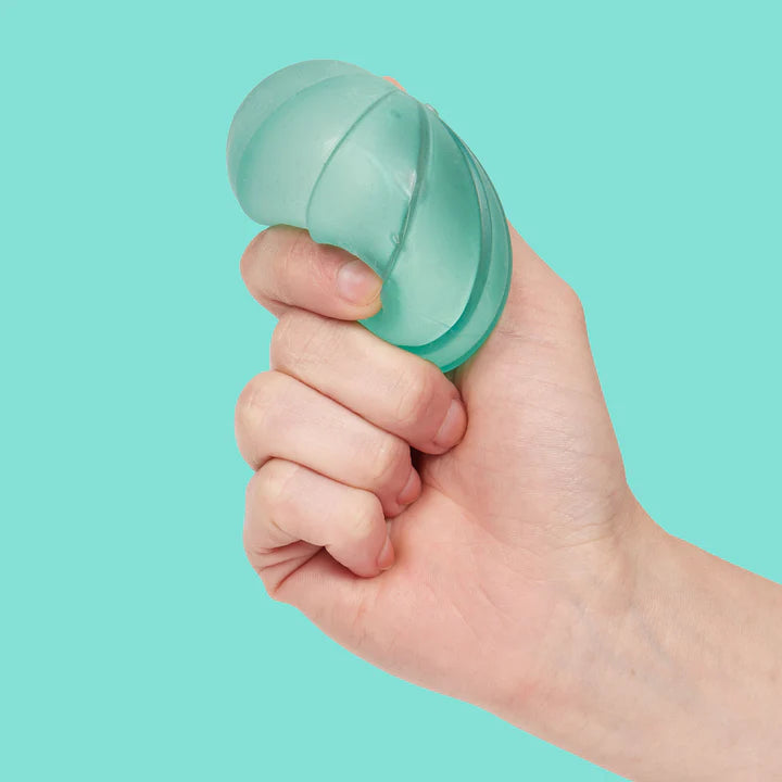Hand squeezing a teal Speks Gump Surface memory gel stress ball against a teal background