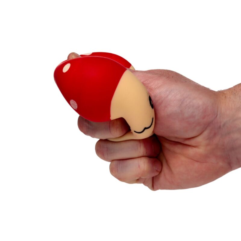 Hand squeezing a red Squeezies Mushroom stress toy to show its soft texture