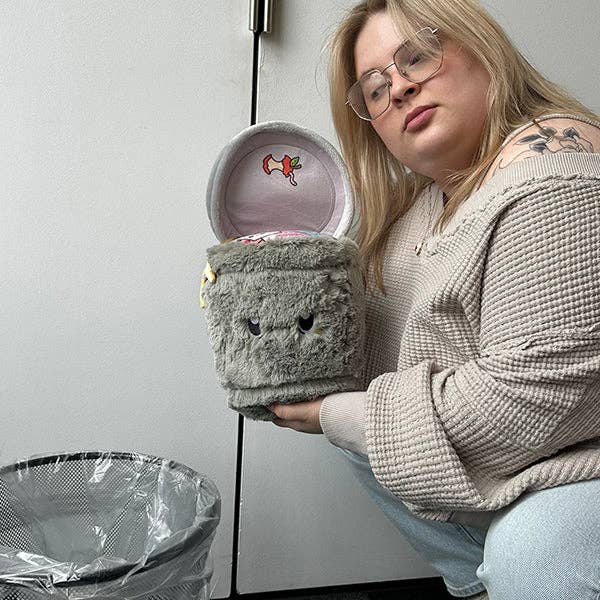 Squishable Mini Trash Can collectible plush held open by woman next to real bin