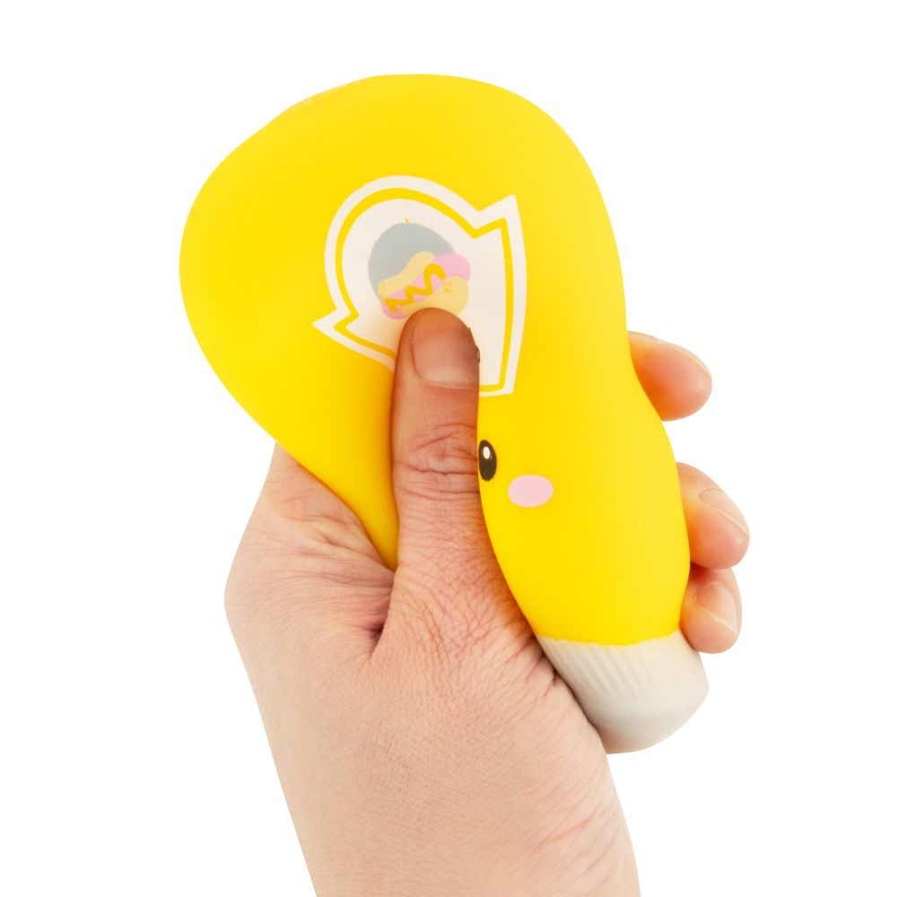 Hand squeezing a yellow kawaii mustard squishy sauce bottle fidget toy, showing it deforming under pressure