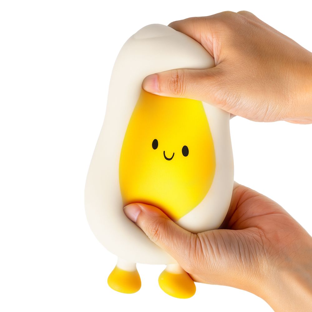Two hands squeezing the Stretch N Smash egg fidget toy, showing the stretchy white material deforming around the yellow yolk