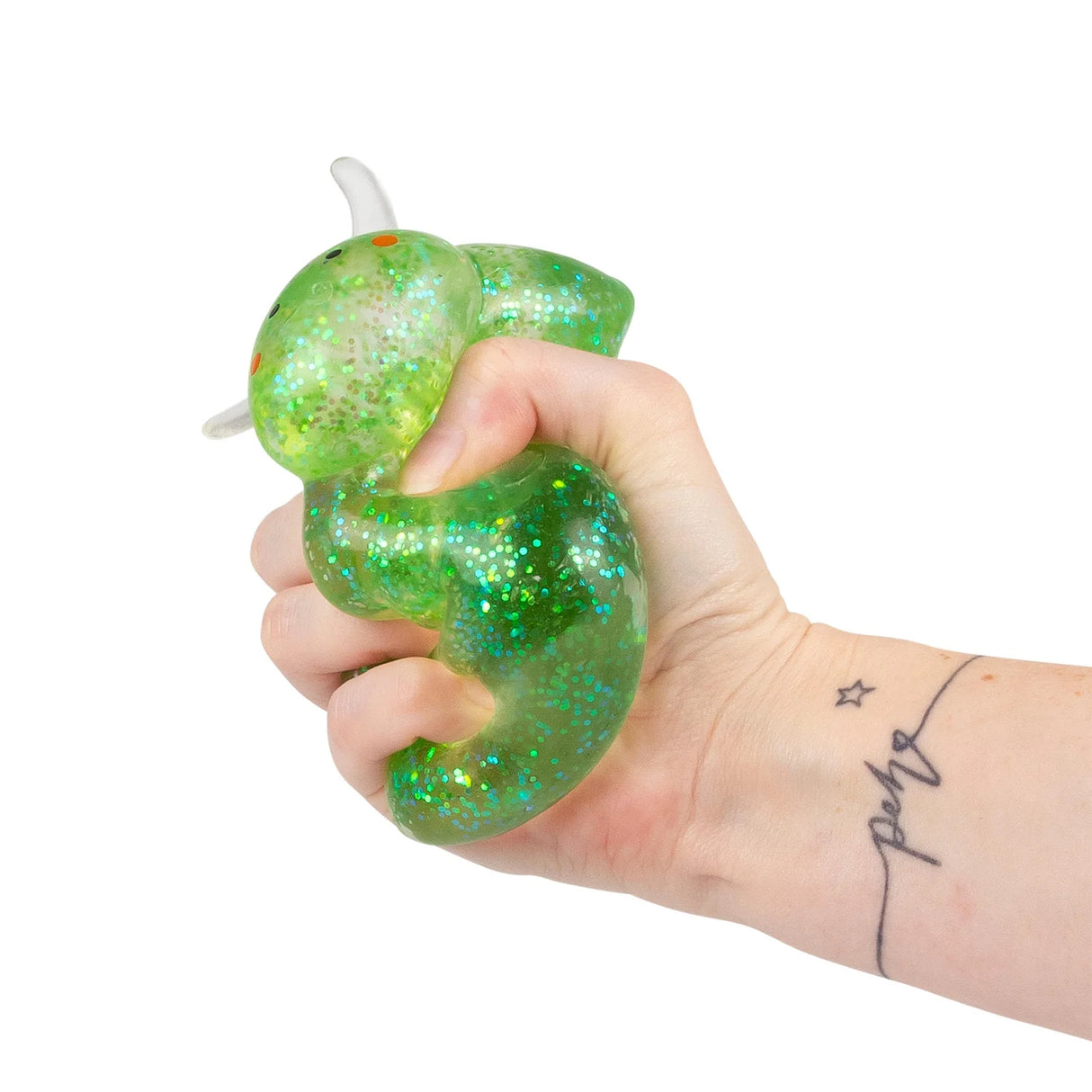 Hand squeezing a green glitter Sugar Sea Sheep squishy fidget toy from above, showing deformation