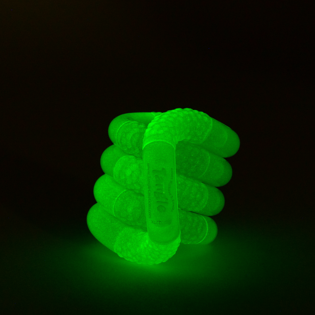 Green glow-in-the-dark Tangle Jr. scaly fidget toy glowing bright green in the dark
