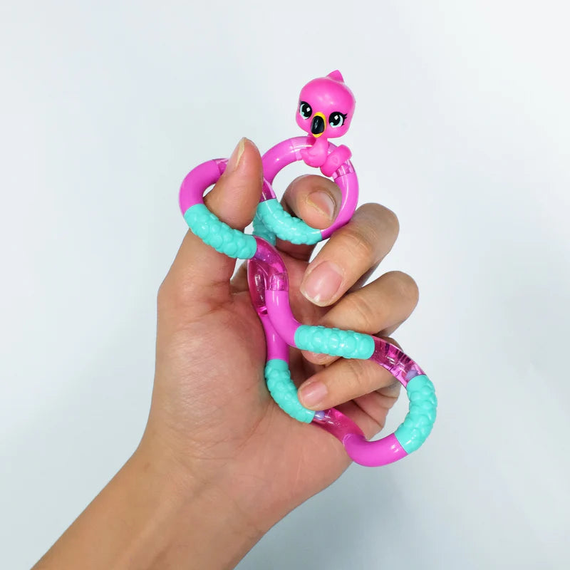 Hand holding a pink and teal flamingo Tangle Jr. Pet fidget toy in a loose grip