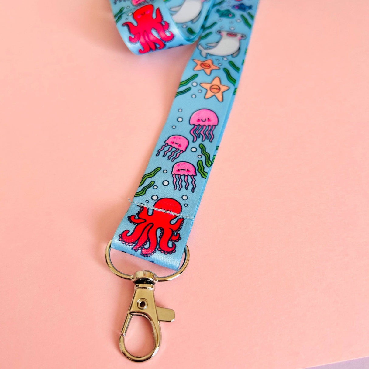 Lanyard with ocean-themed design featuring octopus, jellyfish, and starfish on a pink background