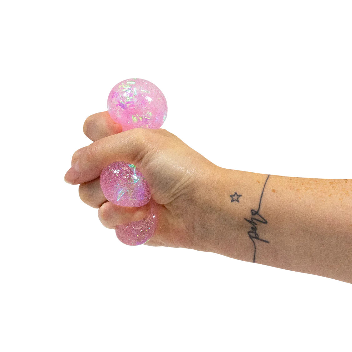 Adult hand squeezing two pink glitter squish balls, showing their soft and pliable texture