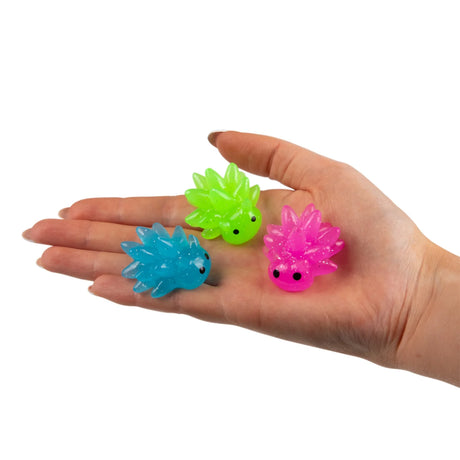 Three glow-in-the-dark sea sheep mini mochi squishies in green, pink and blue resting on an open palm
