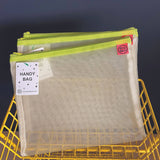 Mesh handy bag with green zipper on a yellow metal basket against a dark background