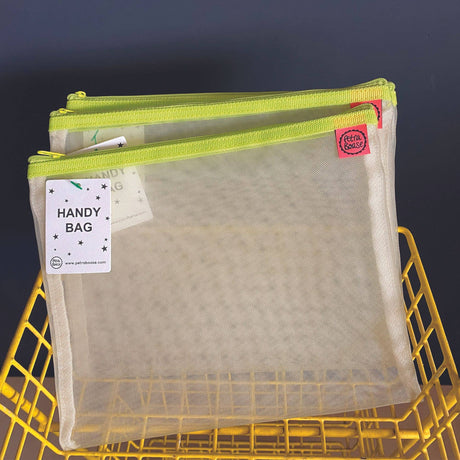 Mesh handy bag with green zipper on a yellow metal basket against a dark background