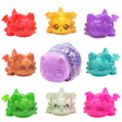 Eight colourful Aphmau MeeMeow squishy dragon figures arranged around their mystery capsule packaging