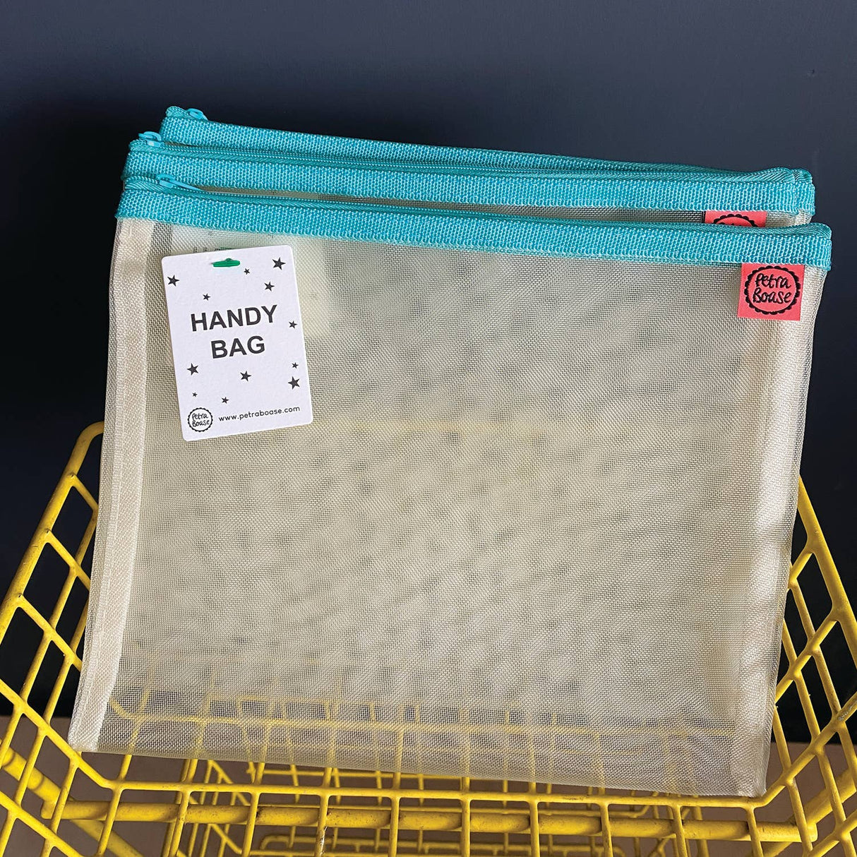 Mesh handy bag with blue zipper on a yellow grid background