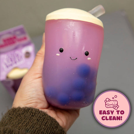 Hand holding the Boba Squish-Tea squishy with easy to clean badge, packaging in background