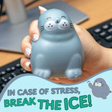 A hand holds a gray seal-shaped stress toy with a cartoon face. The background shows a desk with a keyboard and monitor, and a graphic overlay at the bottom reads 'IN CASE OF STRESS, BREAK THE ICE!' with a small seal illustration.