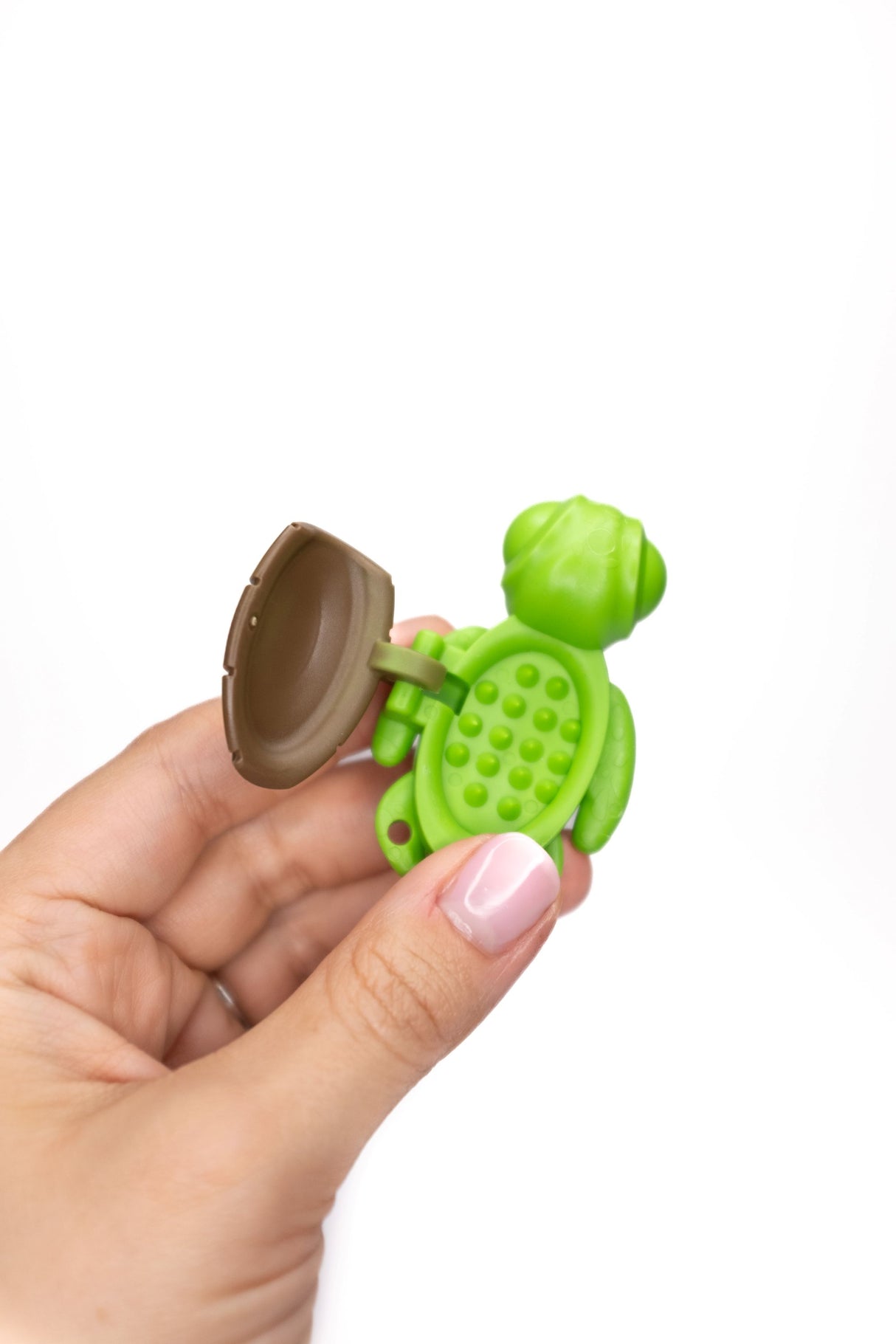 Green Calm Buddi Turtle held open between fingers, spiky inner sensory fidget