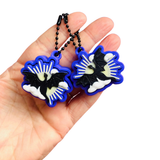 Hand holding two dragon-shaped keychains with blue borders on a white background