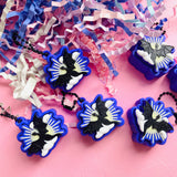 Collection of dragon clicker fidget keychains spread across a pink surface with blue and white confetti
