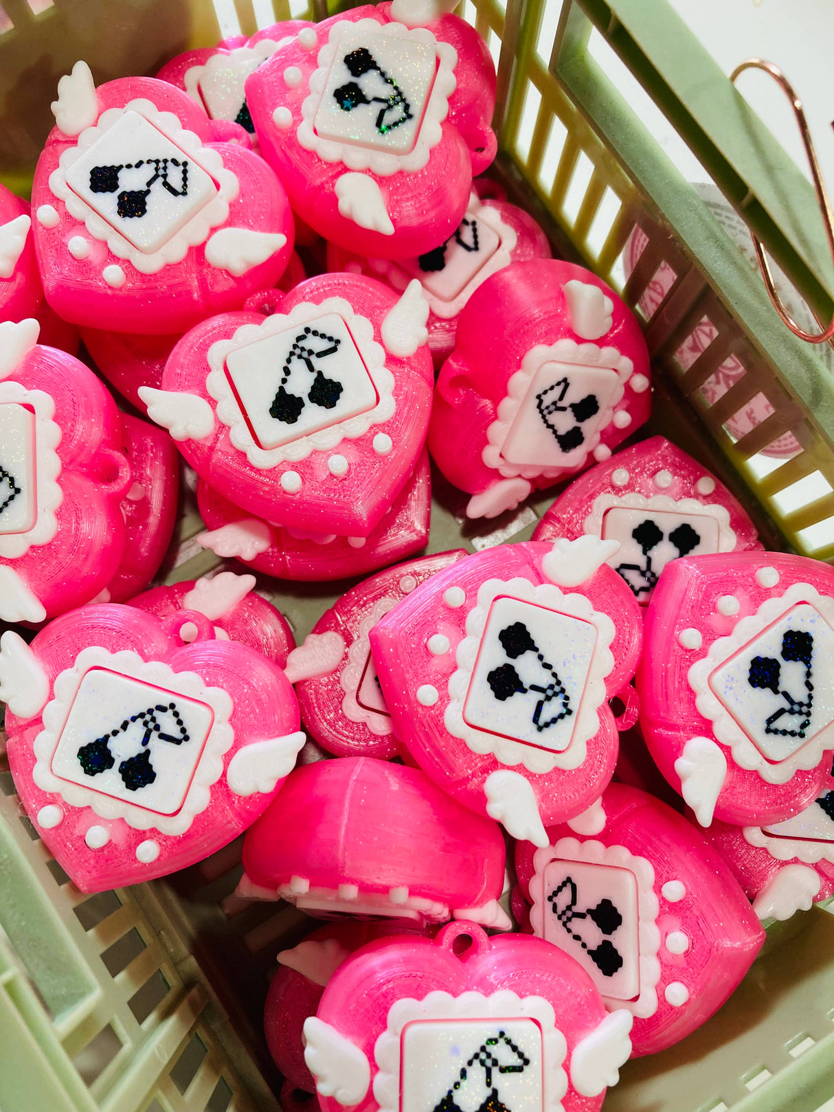 Collection of pink heart clicker fidget keychains filling a small green basket from above