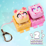 Two small character-shaped keychain clickers on a light blue background with a metal key ring and the text 'Mystery Clickeez 2' in the lower right.