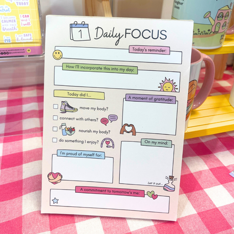Daily Focus notepad displayed in shop setting, pastel mental wellness stationery