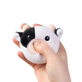 Hand squeezing black and white cow farm animal squishy plush sensory toy demonstrating soft sugar-filled texture